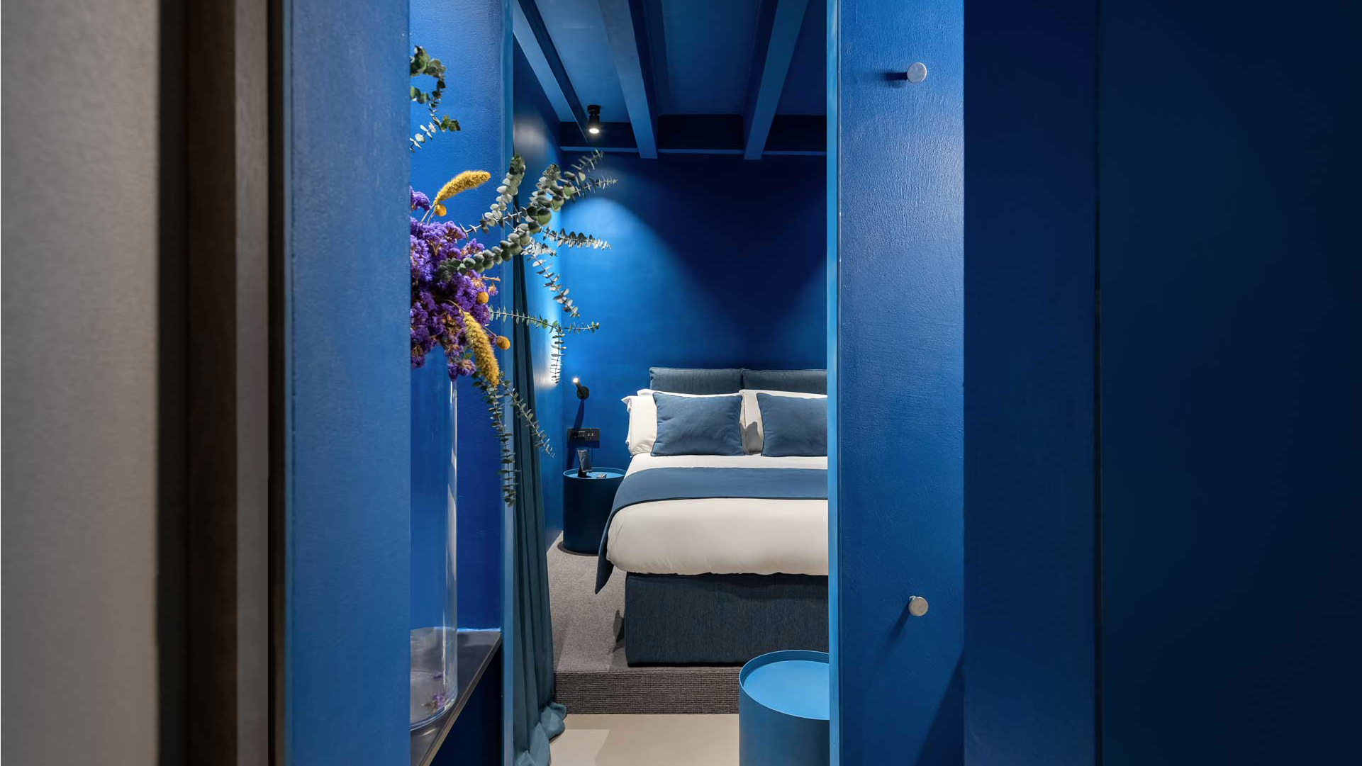Camera con pareti blu e letto matrimoniale, vista dall’ingresso