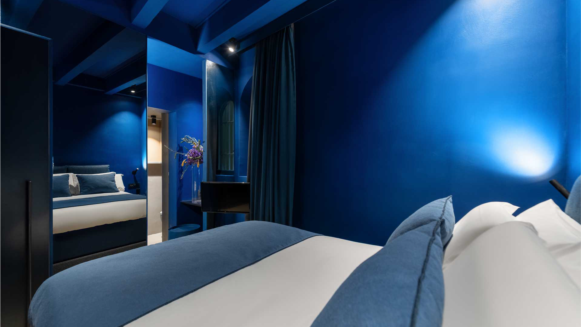 Camera blu con letto matrimoniale e specchio a tutta parete