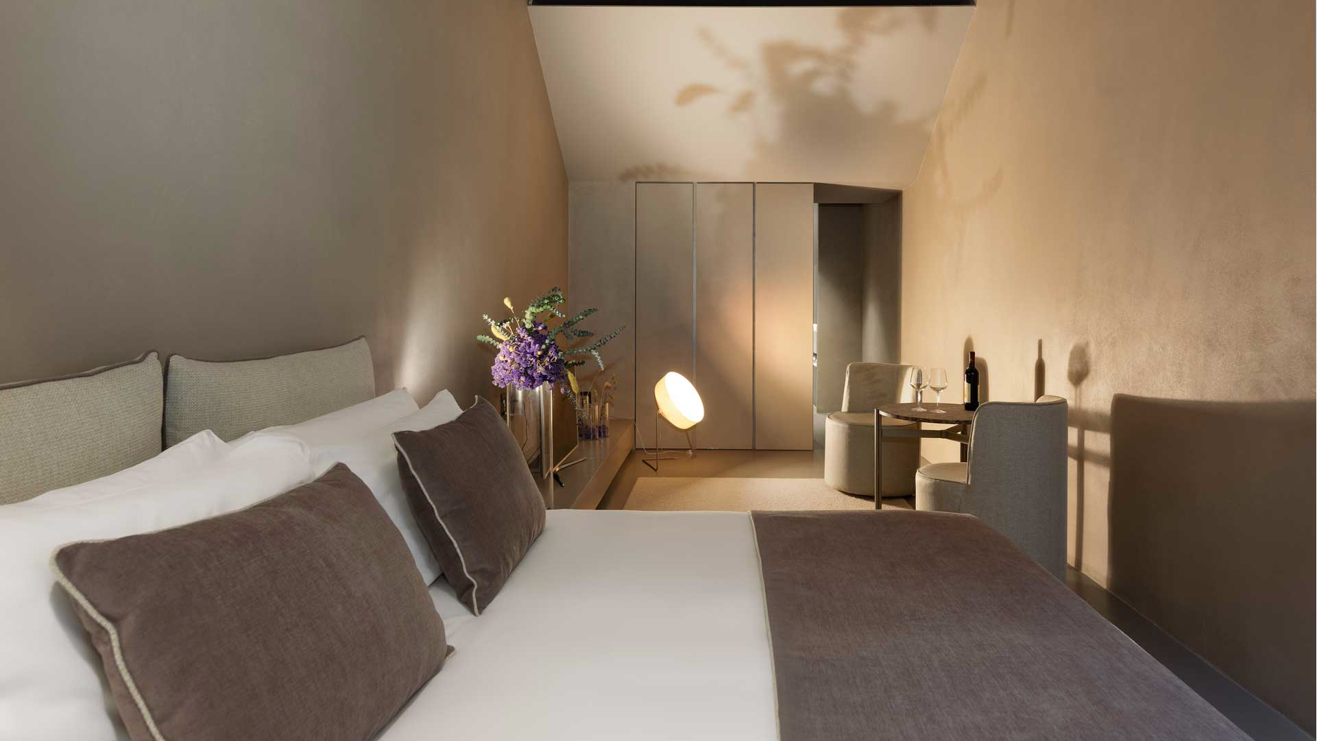 Vista della Camera Tripla Superior: letto matrimoniale, armadio a tutta altezza e angolo relax con poltrone e tavolino.