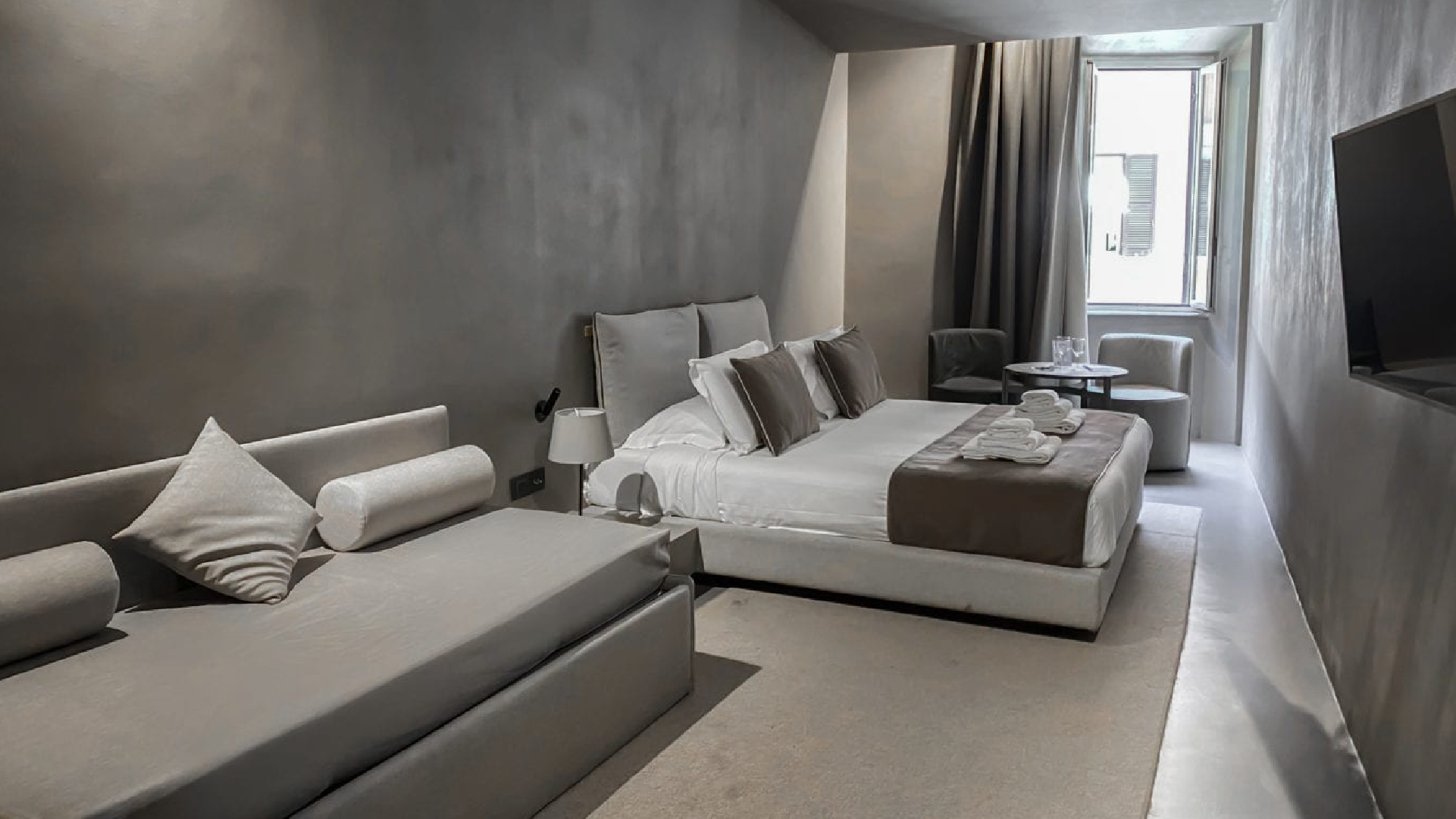 Camera Tripla Superior con letto matrimoniale e divano letto, area relax vicino alla finestra e TV a parete.