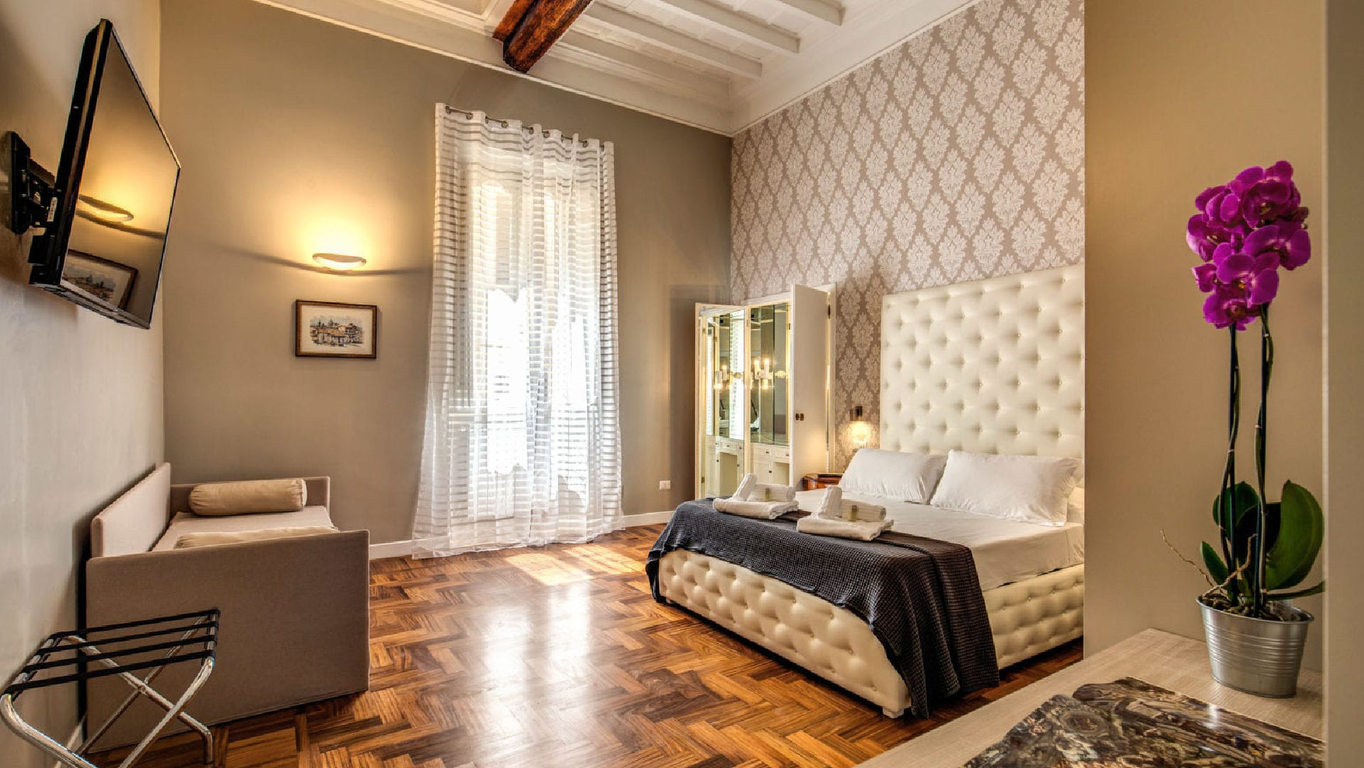 Camera matrimoniale della Suite Executive con letto capitonné, parquet, divanetto e luce naturale, Via Della Croce.