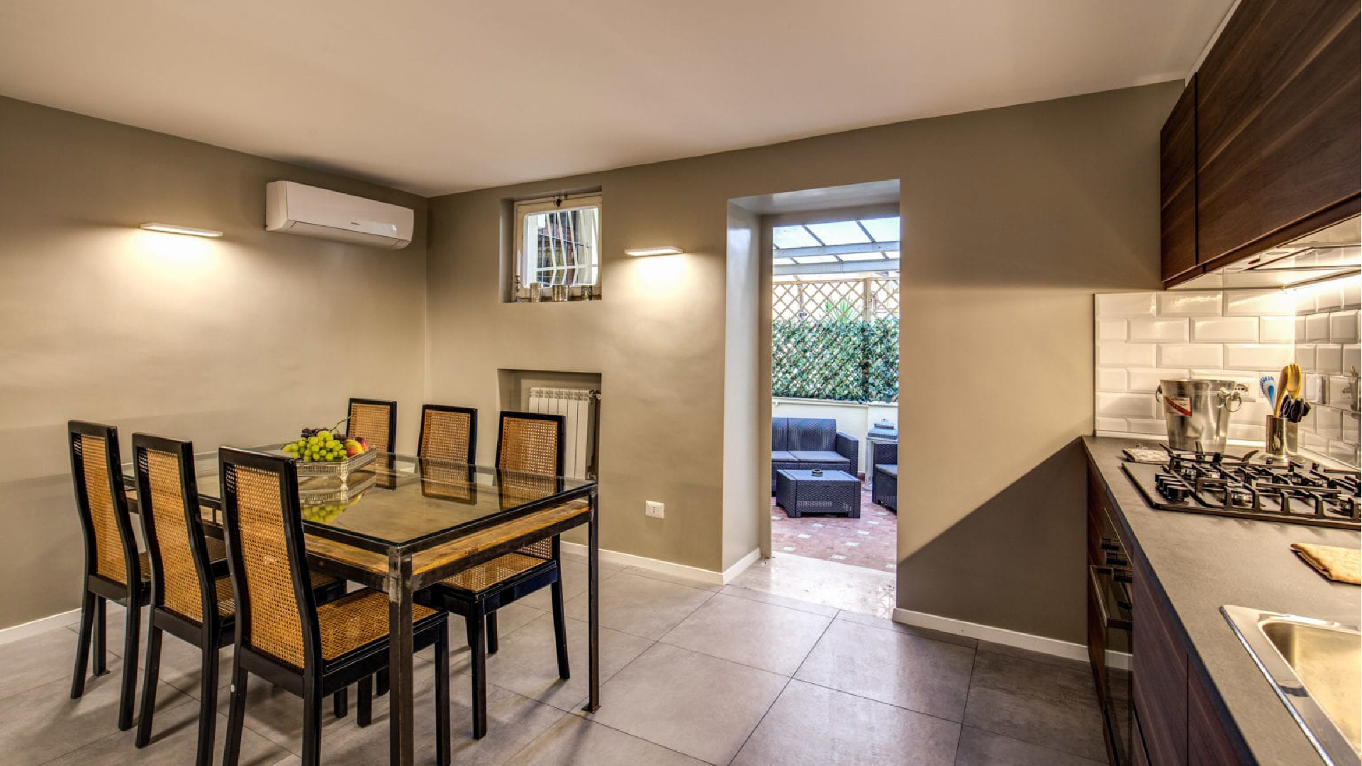 Ambiente living della Suite Executive con cucina attrezzata, zona pranzo e porta finestra che conduce al patio.