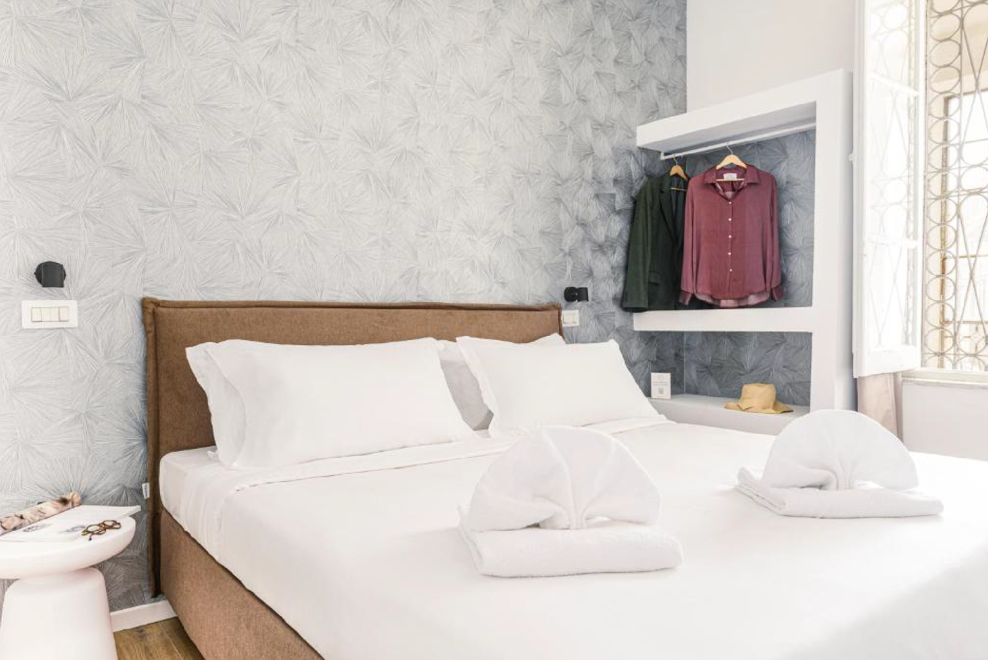 Letto matrimoniale in Suite Standard con parete decorata, nicchia guardaroba a vista e finestra luminosa a Via Mecenate.
